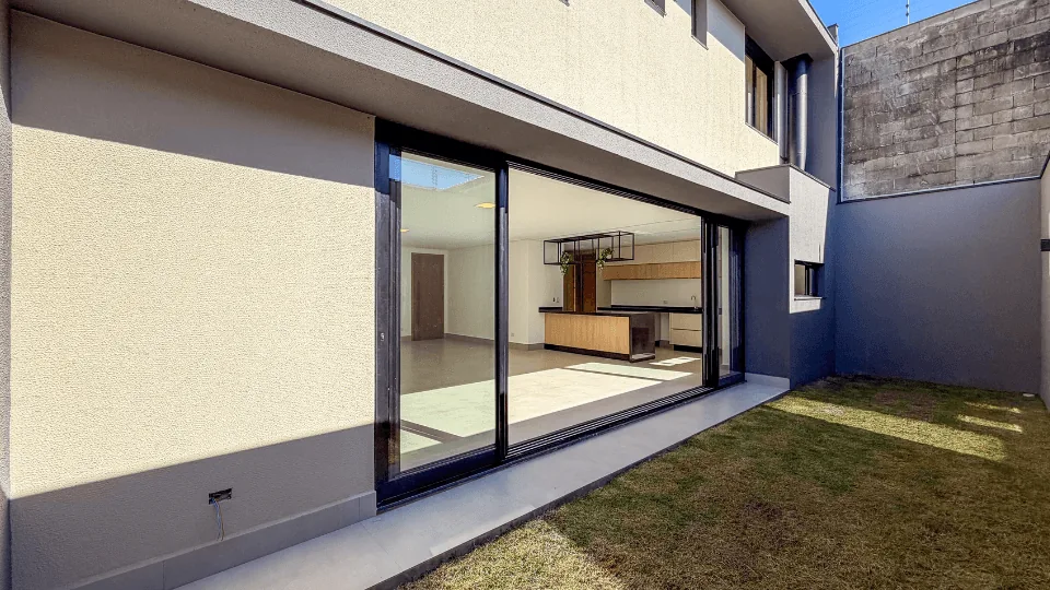 Área externa da Casa 01 com deck, jardim e porta de vidro integrando com o living
